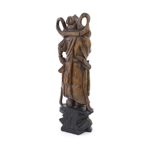 1024 - A Chinese carved wooden model of a standing figure with a sword. Approx. 16