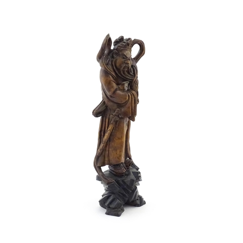 1024 - A Chinese carved wooden model of a standing figure with a sword. Approx. 16