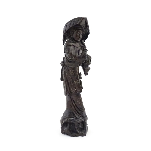 1025 - An Oriental carved hardwood figure with inlaid wirework detail, the carved naturalistic base with fi... 