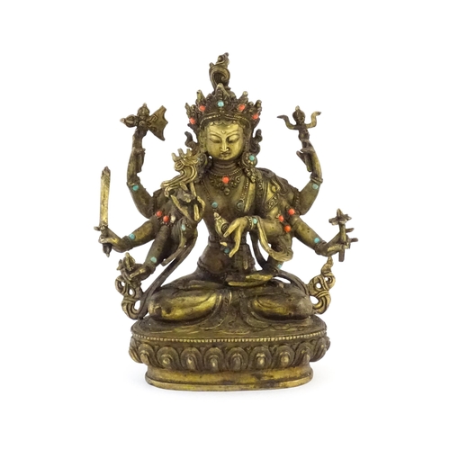 1043 - A Tibetan cast bronze figure of Guanyin with eight arms holding various symbols to include ruyi, flo... 