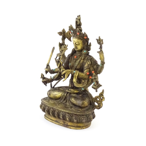 1043 - A Tibetan cast bronze figure of Guanyin with eight arms holding various symbols to include ruyi, flo... 