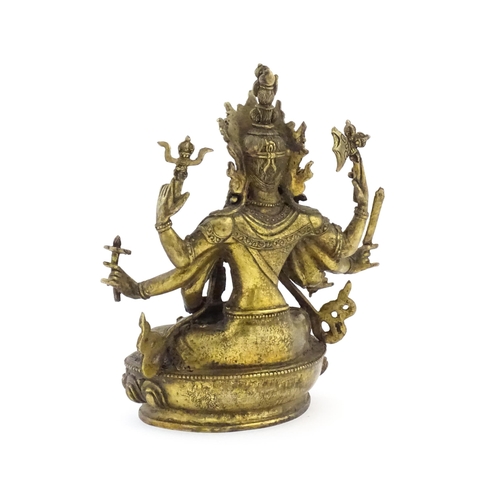 1043 - A Tibetan cast bronze figure of Guanyin with eight arms holding various symbols to include ruyi, flo... 