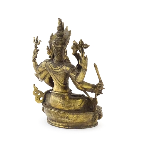 1043 - A Tibetan cast bronze figure of Guanyin with eight arms holding various symbols to include ruyi, flo... 