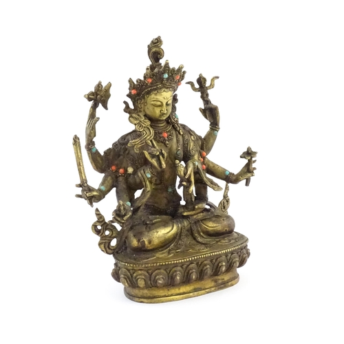 1043 - A Tibetan cast bronze figure of Guanyin with eight arms holding various symbols to include ruyi, flo... 