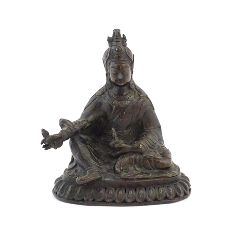 1044 - A Tibetan cast bronze model of the Buddhist master Padmasambhava / Guru Rinpoche seated holding the ... 