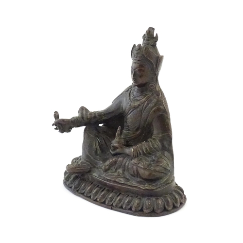 1044 - A Tibetan cast bronze model of the Buddhist master Padmasambhava / Guru Rinpoche seated holding the ... 