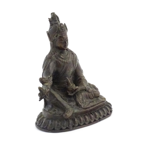 1044 - A Tibetan cast bronze model of the Buddhist master Padmasambhava / Guru Rinpoche seated holding the ... 