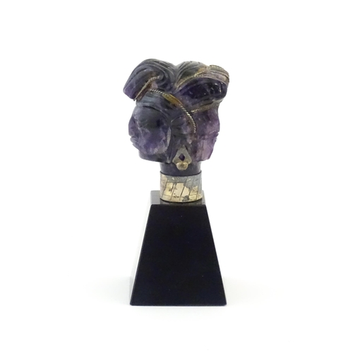 1048 - A 20thC amethyst carving modelled as a male head with headdress, mounted on a tapering plinth. Appro... 