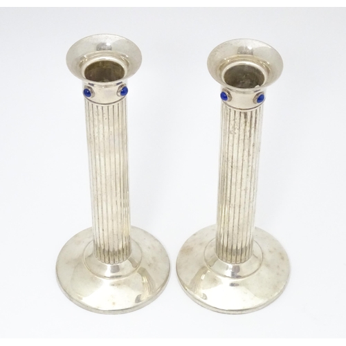 428 - A pair of silver plate candlesticks of fluted column form, each set with four lapis lazuli cabochon.... 