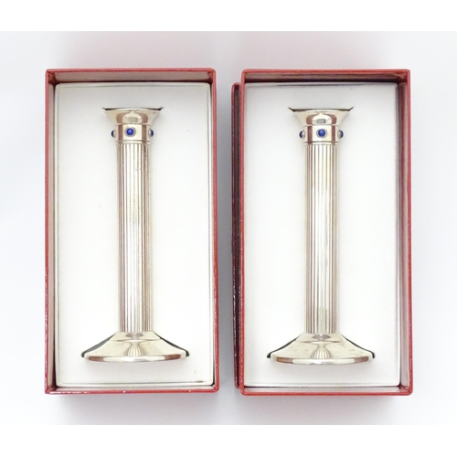 428 - A pair of silver plate candlesticks of fluted column form, each set with four lapis lazuli cabochon.... 