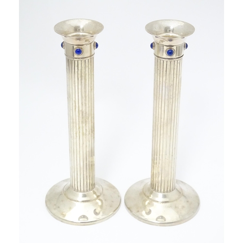 428 - A pair of silver plate candlesticks of fluted column form, each set with four lapis lazuli cabochon.... 