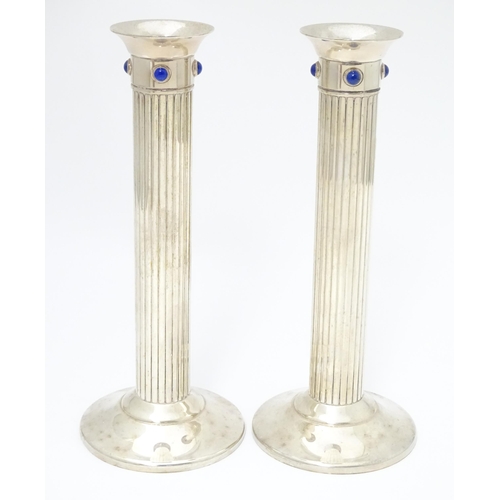 428 - A pair of silver plate candlesticks of fluted column form, each set with four lapis lazuli cabochon.... 