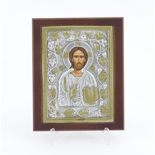 1052 - A 20thC Russian icon depicting Jesus Christ within an embossed surround bordered by fruiting vine de... 