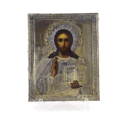 1054 - A 19thC Russian oil on panel icon depicting Christ Pantocrator with an embossed silver surround with... 