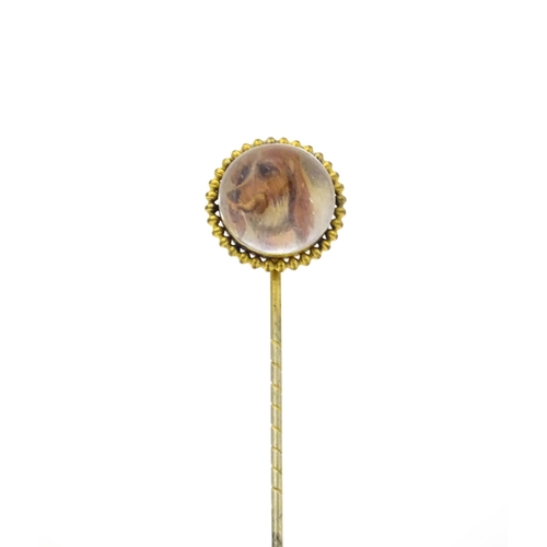 666 - A gilt metal stick pin surmounted by an Essex Crystal cabochon with dog head decoration. Cabochon ap... 