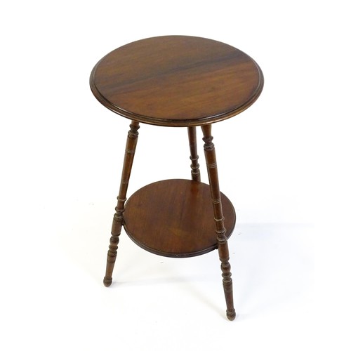 1369 - A late 19thC / early 20thC walnut lamp table with a circular moulded top above a smaller under tier ... 