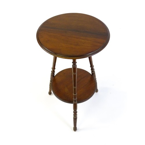 1369 - A late 19thC / early 20thC walnut lamp table with a circular moulded top above a smaller under tier ... 