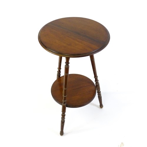 1369 - A late 19thC / early 20thC walnut lamp table with a circular moulded top above a smaller under tier ... 