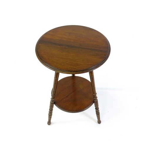 1369 - A late 19thC / early 20thC walnut lamp table with a circular moulded top above a smaller under tier ... 