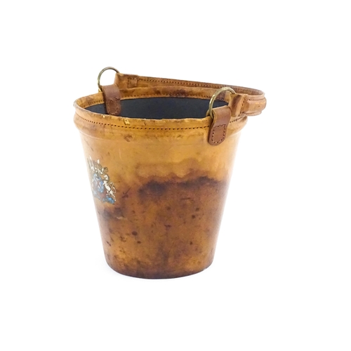 1149 - A 20thC leather covered fire bucket with swing handle and armorial / coat of arms detail. Approx. 11... 