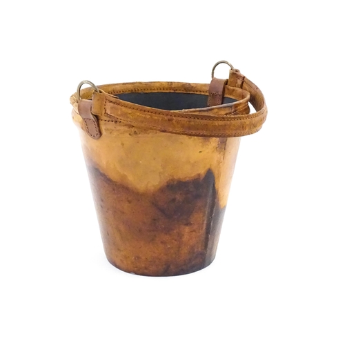 1149 - A 20thC leather covered fire bucket with swing handle and armorial / coat of arms detail. Approx. 11... 