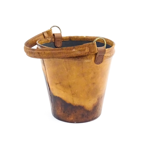 1149 - A 20thC leather covered fire bucket with swing handle and armorial / coat of arms detail. Approx. 11... 