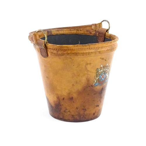 1149 - A 20thC leather covered fire bucket with swing handle and armorial / coat of arms detail. Approx. 11... 