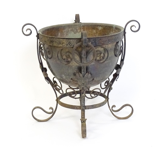 1202 - A late 19th / early 20thC copper planter / jardiniere within a wrought iron stand with scrollwork an... 