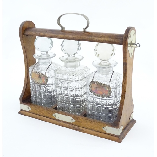 1204 - A late 19th / early 20thC oak tantalus with silver plate mounts, containing three glass decanters an... 