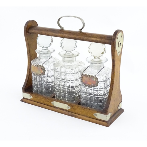 1204 - A late 19th / early 20thC oak tantalus with silver plate mounts, containing three glass decanters an... 