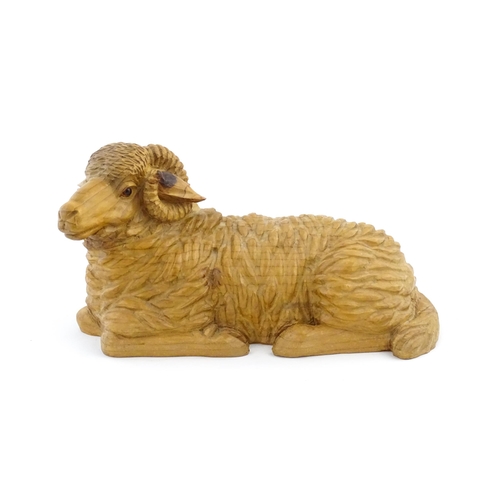 1230 - A 20thC carved wooden model of a recumbent ram / sheep. Approx. 21