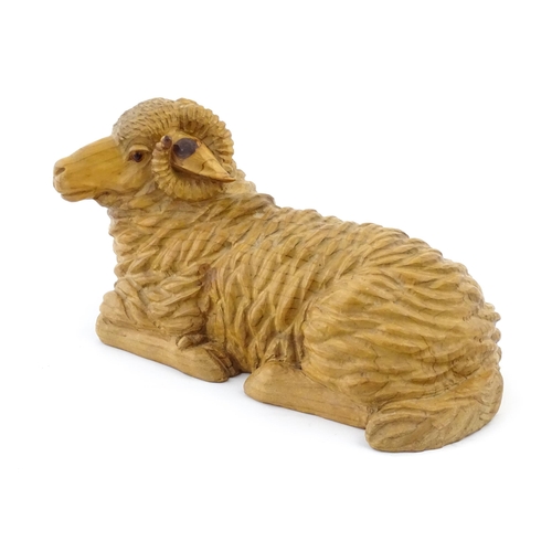 1230 - A 20thC carved wooden model of a recumbent ram / sheep. Approx. 21