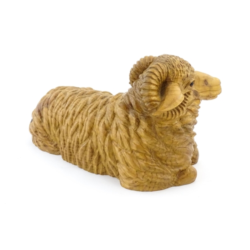 1230 - A 20thC carved wooden model of a recumbent ram / sheep. Approx. 21