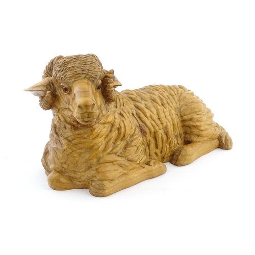 1230 - A 20thC carved wooden model of a recumbent ram / sheep. Approx. 21