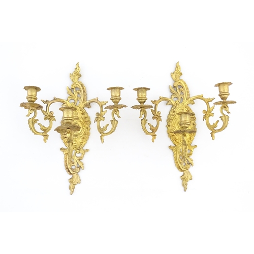 1241 - A pair of late 19th / early 20thC gilt metal three branch wall candle sconces with scrolling foliate... 