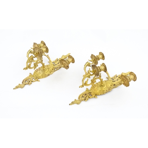 1241 - A pair of late 19th / early 20thC gilt metal three branch wall candle sconces with scrolling foliate... 