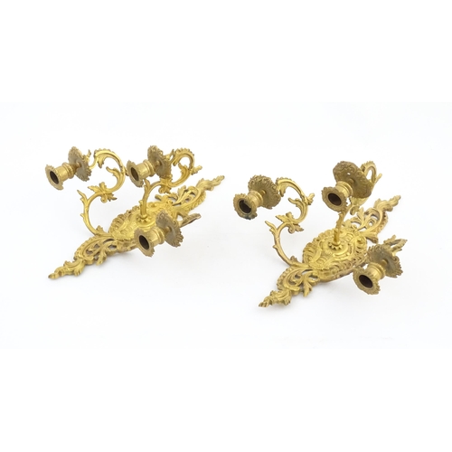 1241 - A pair of late 19th / early 20thC gilt metal three branch wall candle sconces with scrolling foliate... 