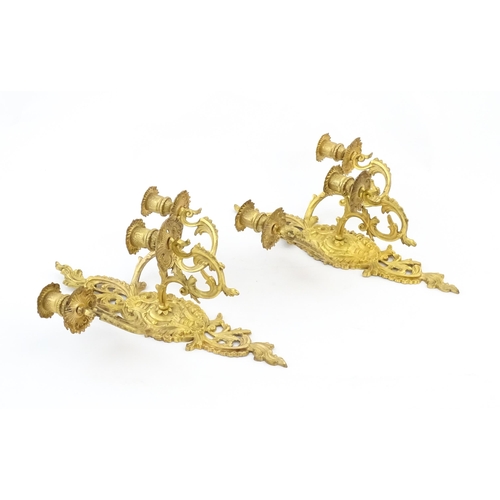 1241 - A pair of late 19th / early 20thC gilt metal three branch wall candle sconces with scrolling foliate... 