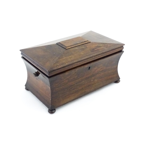 1197 - A 19thC rosewood tea caddy of sarcophagus form raised on four squat bun feet, the hinged lid opening... 