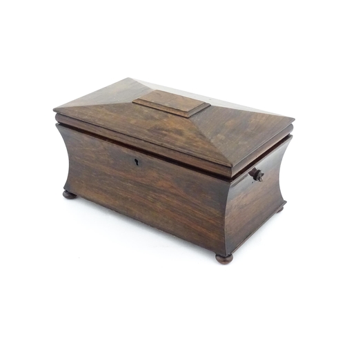 1197 - A 19thC rosewood tea caddy of sarcophagus form raised on four squat bun feet, the hinged lid opening... 