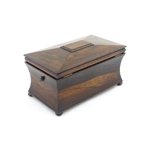 1197 - A 19thC rosewood tea caddy of sarcophagus form raised on four squat bun feet, the hinged lid opening... 