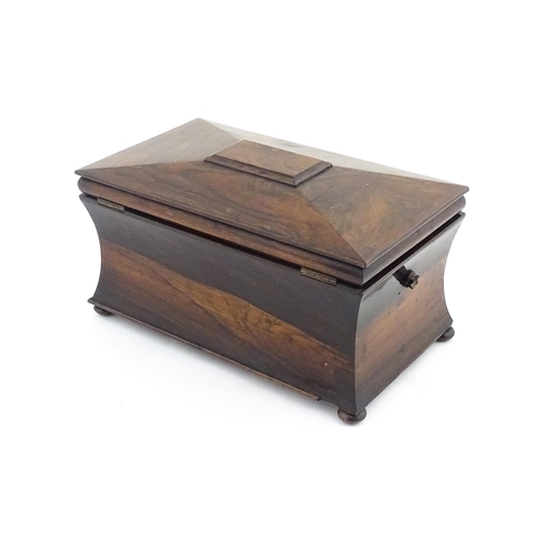 1197 - A 19thC rosewood tea caddy of sarcophagus form raised on four squat bun feet, the hinged lid opening... 