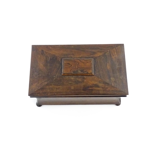 1197 - A 19thC rosewood tea caddy of sarcophagus form raised on four squat bun feet, the hinged lid opening... 