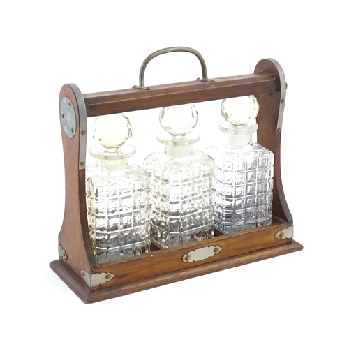 1198 - A 20thC oak tantalus with three glass decanters. Approx. 12