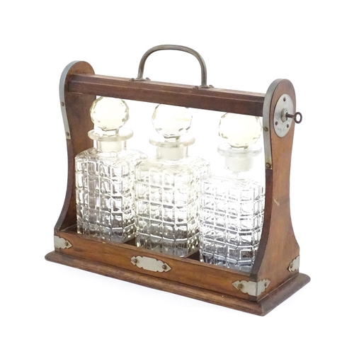 1198 - A 20thC oak tantalus with three glass decanters. Approx. 12