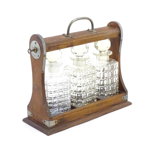 1198 - A 20thC oak tantalus with three glass decanters. Approx. 12