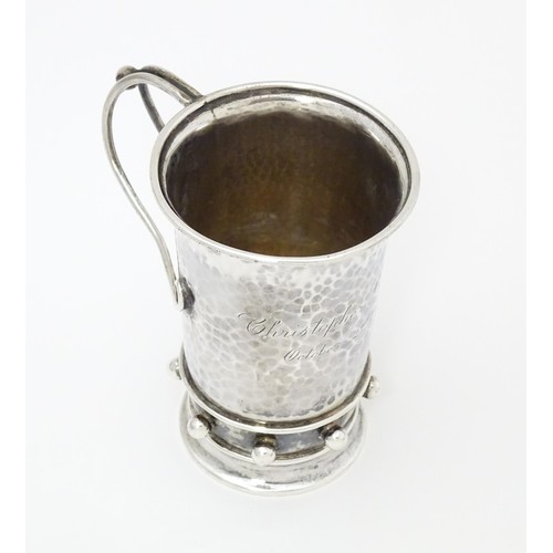 404 - An Arts & Crafts silver christening mug with hammered decoration, banded spherical ball detail and b... 