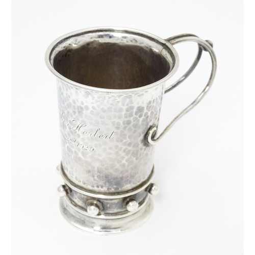 404 - An Arts & Crafts silver christening mug with hammered decoration, banded spherical ball detail and b... 