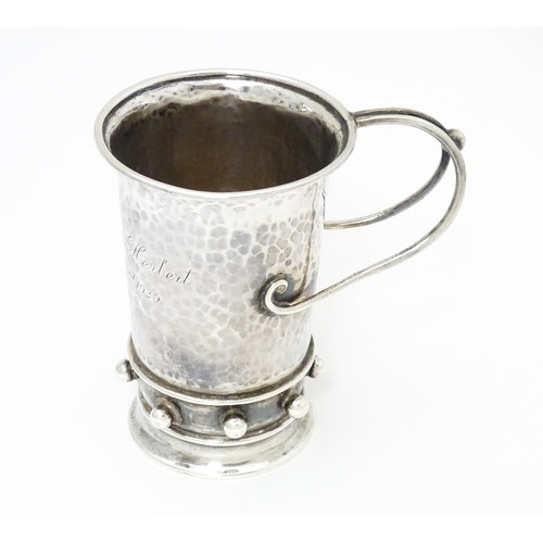 404 - An Arts & Crafts silver christening mug with hammered decoration, banded spherical ball detail and b... 