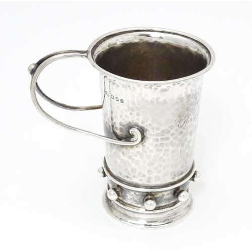 404 - An Arts & Crafts silver christening mug with hammered decoration, banded spherical ball detail and b... 